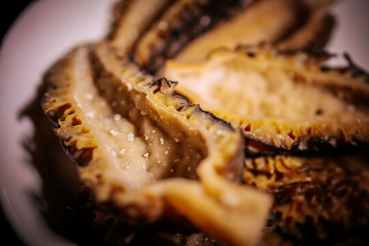 Extreme close-up of cooked moren pieces of mushrooms and flesh with golden tones, shiny texture, shallow focus and visible details.