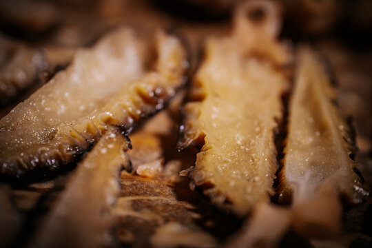 Macro close-up of sliced ​​cooked moren mushrooms with a shiny texture, warm brown tones, shallow focus and rustic culinary details.
