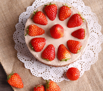 Overhead strawberry cake with fresh berries and creamy frosting on rustic table