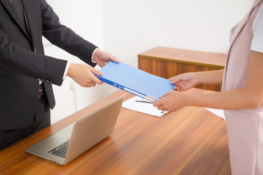 Business colleagues handing over document folder in office