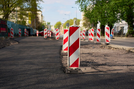 Row of vertical delineators marking a lane closure during urban infrastructure repair and paving.