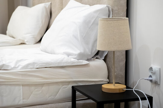 Minimalist table lamp on a nightstand next to a modern bed, conveying a sense of comfort, relaxation, and serenity in a contemporary bedroom interior design for lifestyle concepts