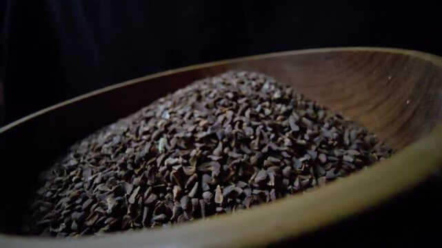 Close-up of dried Syrian Rue seeds (Peganum harmala) in a rustic wooden bowl, dark background, cinematic lighting, organic herbal texture.