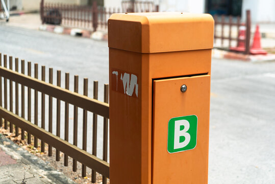 Orange letterbox on side of street with fence