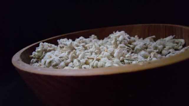 Macro shot of dried Teucrium polium (Felty Germander), a medicinal mountain herb from the Saudi desert used in folk medicine and blood sugar regulation, served in a wooden bowl.