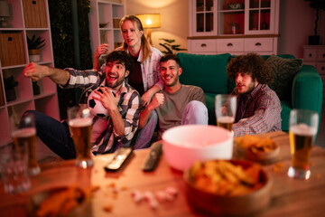 Friends cheering watching soccer game together at home © Zoran Jesic