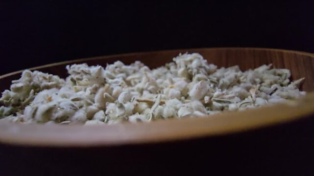 Macro shot of dried Teucrium polium (Felty Germander), a medicinal mountain herb from the Saudi desert used in folk medicine and blood sugar regulation, served in a wooden bowl.