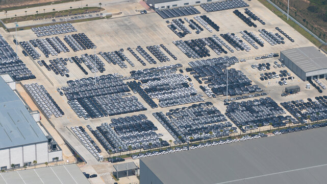 Aerial view of BYD Thailand Rayong Office Building and a vast parking lot filled with thousands of new electric vehicles organized in rows next to industrial warehouses Phananikhom, Rayong, Thailand.