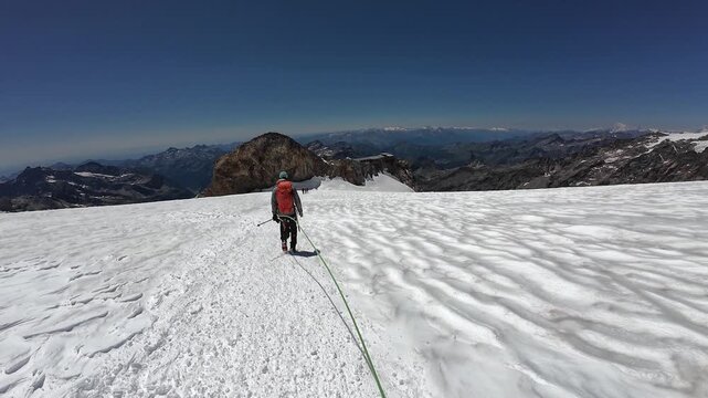 POV mountaineering in rope team with mountaineer and mountain glacier panorama descending towards refuge Gnifetti Hut with summit Gran Paradiso (background) in summer in Pennine Alps, Italy
