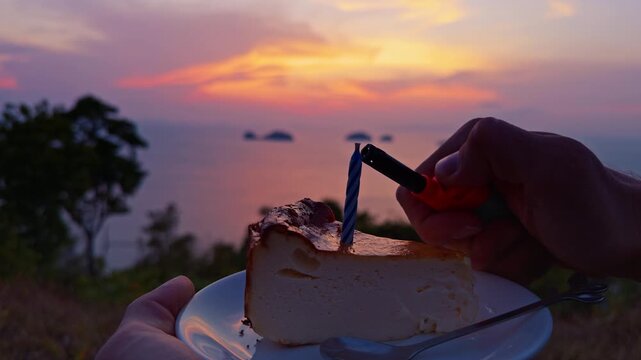 First person view of hand trying to light candle on dessert with lighter but flame does not ignite at sunset over sea, unsuccessful attempt and evening mood
