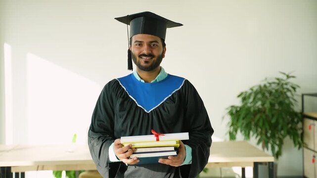 Proud Indian male graduate holding books and diploma