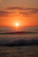 Fototapeta premium Golden sunset over ocean waves with dramatic orange sky