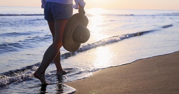 Happy woman is walking on the sandy beach in a red dress against sunrise. Slow motion