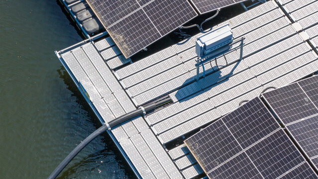 Aerial view of floating solar panels on a platform with metal walkways and electrical cables on the water surface in Zwolle, Overijssel, Netherlands.