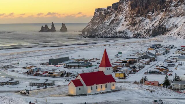 Vik i Myrdal church and Reynisdrangar sea stacks at snowy sunset, Iceland