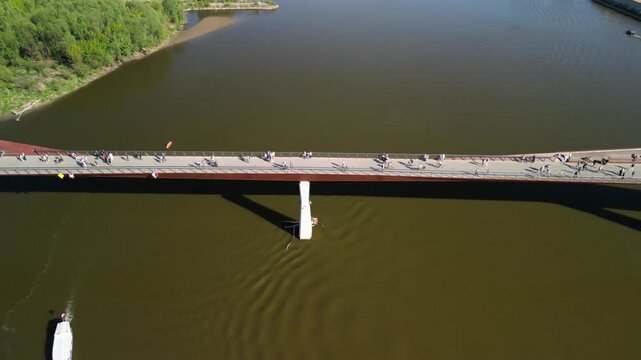 Warszawa - Polska - panorama miasta i kładka pieszo rowerowana na rzece Wisła nagrane dronem. Słońce, panorama miasta, drapacze chmur, krajobraz miasta z drona