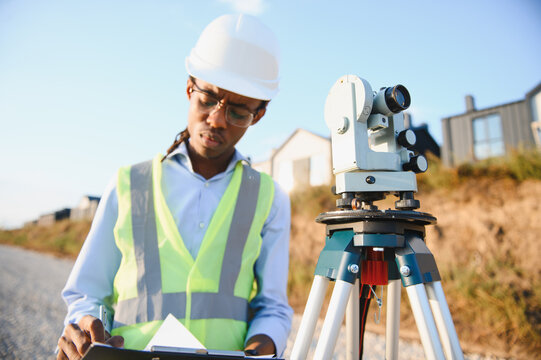 Surveyor checking data near leveling instrument