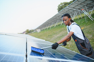 Black man cleaning solar panel array © Serhii