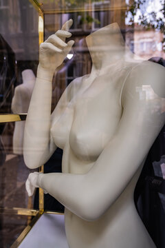 Headless naked female mannequin bust in a shop window.