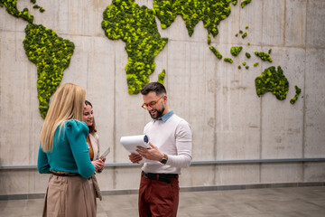 Business colleagues collaborating in office with global moss wall © Migma_Agency