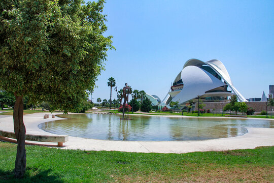 Futuristic architecture of modern opera house building with reflection in water pool and green trees in city park. Valencia, Spain, Mediterranean.