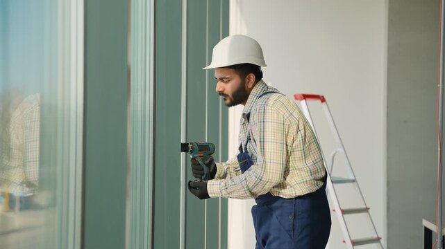 Construction worker using power drill on building facade