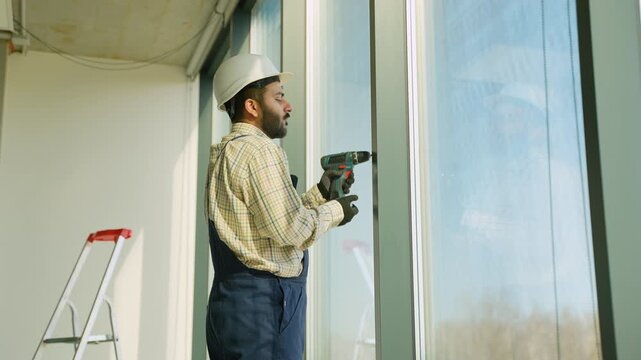 Construction worker installing window frame with cordless drill