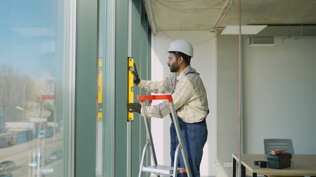 Construction worker using spirit level on a window
