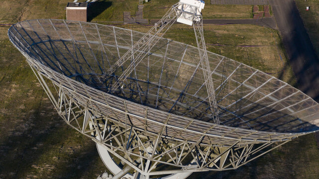 Aerial view of the Westerbork Synthesis Radio Telescope showing the massive parabolic dish and intricate metal framework over green fields Zwiggelte, Drenthe, Netherlands.