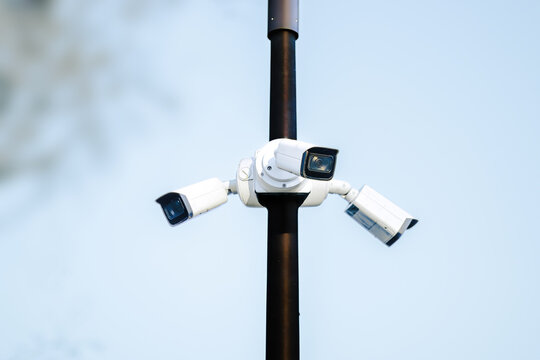 Security camera system mounted on a pole with multiple cameras positioned for surveillance against a clear blue sky background