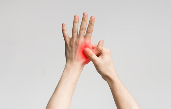 Young man suffering from pain in palms, massaging his painful hand from symptoms of Peripheral Neuropathy