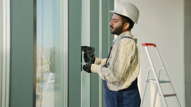 Construction worker installing window frame with power drill
