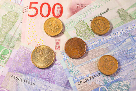Swedish krona banknotes and coins arranged as colorful financial background representing Scandinavian economy.