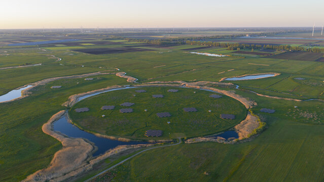 Aerial view of the LOFAR superterp radio telescope station featuring circular antenna arrays on a green island surrounded by water and vast agricultural fields Buinen, Drenthe, Netherlands.