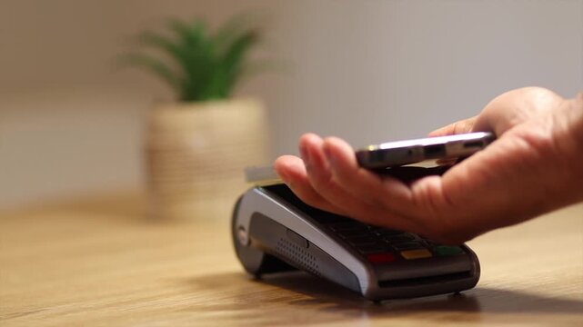 Customer using smartphone for contactless payment with nfc technology at a pos terminal, simplifying the checkout process and making purchases quick and secure
