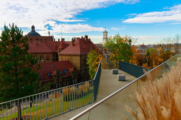 Obraz premium Urban balcony viewpoint overlooking historic town with autumn foliage and blue sky