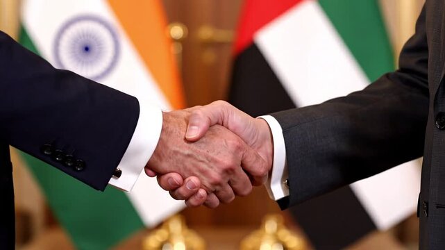 Handshake between two businessmen in front of India and UAE flags