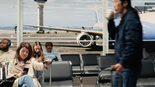 Man bumping into woman while pushing trolley, navigating crowded airport hallway. Travelers clashing luggage while rushing through busy transportation hub to catch plane, camera A