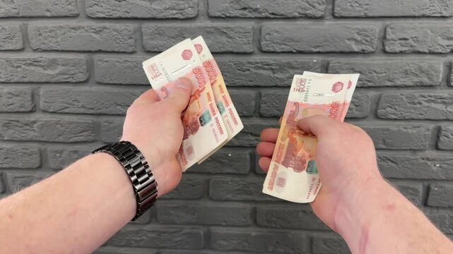 Man counts red paper 5000 rubles bills. Russian cash money in male hand. A man holds a wad of money in his hands. A close-up of a man's hands counts a bundle of bills for five thousand Russian rubles.