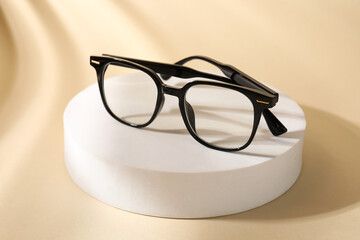 Stylish presentation of eyeglasses on beige background, closeup