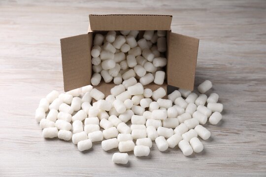 Cardboard box with styrofoam pieces on wooden background