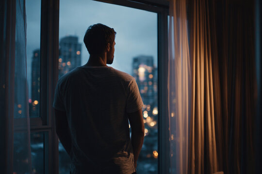 Lonely man looking out window in city apartment, mental health struggle, emotional isolation and anxiety