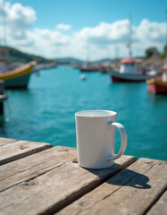 Fototapeta premium White mug sits on old wooden dock. Calm blue water and boats are in distance. Sunny day outdoors. Peaceful seaside view with drink.