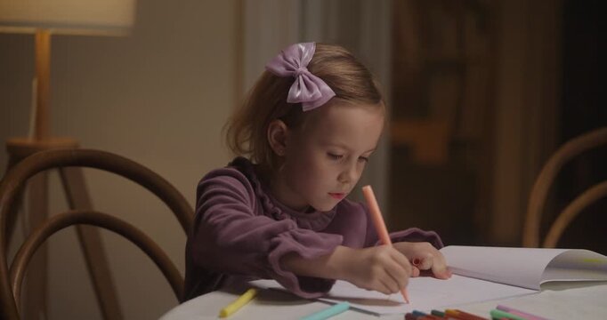 Young artist joyfully brings ideas to life with crayons at a warmly lit table while parents enjoy their time nearby