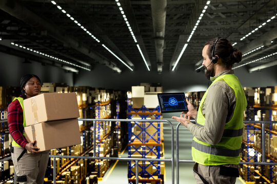 Male employee operating AI-powered systems on tablet, managing customer service calls for parcel tracking info. Man ensuring order fulfillment with artificial intelligence, machine learning.