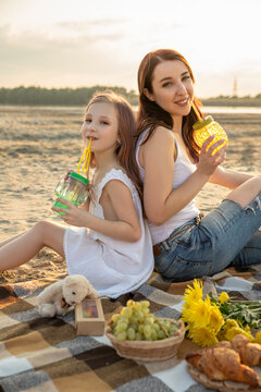 Mother and daughter drink lemonade outdoors. Woman and little girl spend time together on picnic. Mom and her child. Family concept. Selective focus.