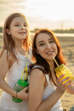 Mother and daughter drink lemonade outdoors. Woman and little girl spend time together on picnic. Mom and her child. Family concept. Selective focus.