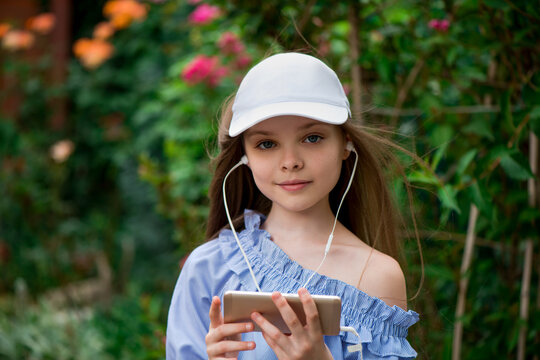 Cute little girl texting or playing games on smart phone outside.