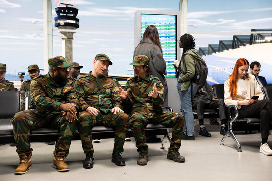 Chatting, going home and patriotic army soldiers sitting on airport lounge bench. Waiting for plane, long military deployment and service members talking, preparing for homecoming reunion