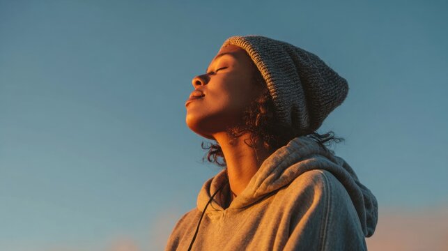 Young woman with eyes closed enjoying golden hour sunlight on her face